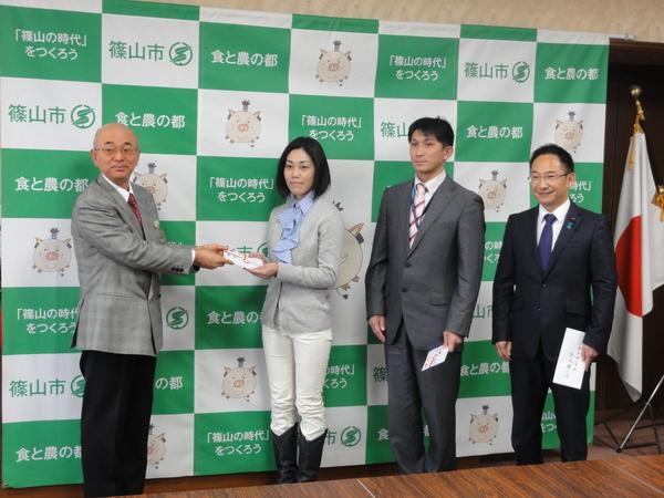 市長が梛野 泰子さんに奨励金を手渡し、俣野 秀明さんも奨励金を左手に持っており、小西 隆紀さんは親書を手に持っている様子の写真
