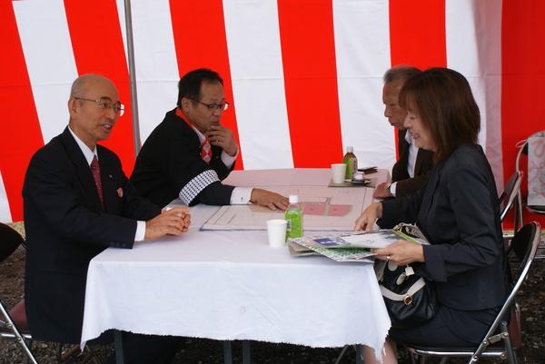 法被を着ている男性が来場者に資料の説明をしている横で市長も話をしている写真