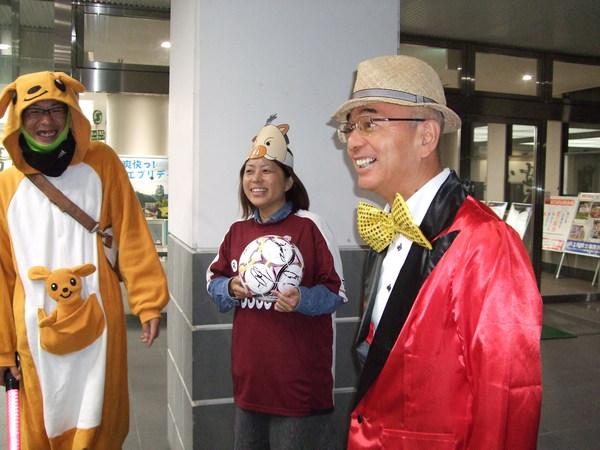 カンガルーの着ぐるみを着た男性、豚のお面にサッカーボールを持った女性、赤の衣装に蝶ネクタイをした市長の写真