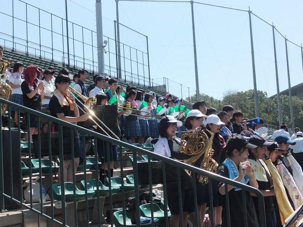 吹奏楽部の生徒が、応援する生徒の横で、演奏している写真