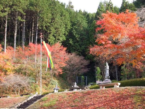 オレンジの紅葉、銅像、吹き流しと緑の木に囲まれた写真