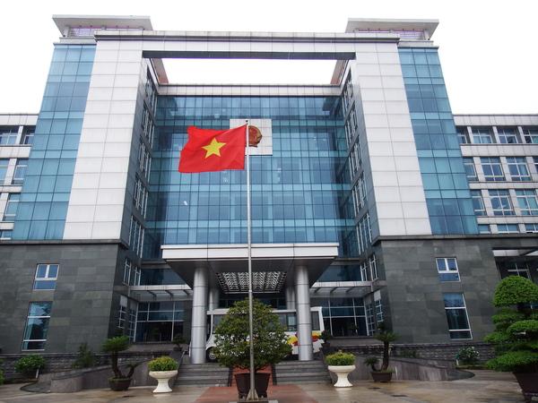 大きな建物の前にベトナムの国旗が掲げられている市役所の写真