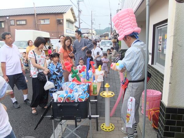 バルーンアートで作った帽子を被った男の人が子供達に作っている写真