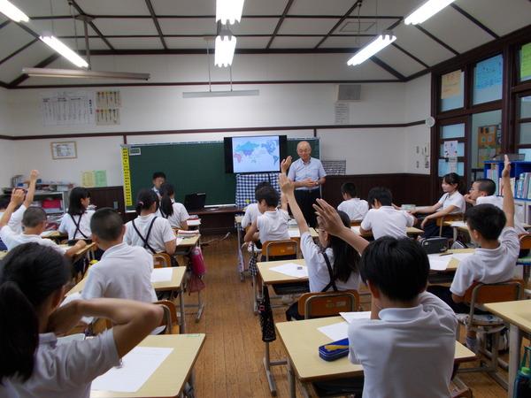 市長が教壇に立ち子供達が手を上げている写真