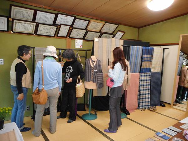 飾られた木綿製品を手に取り見ている複数の女性の写真