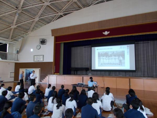 スクリーンに昔の軟式野球部が映し出されそれを生徒たちが見ている写真