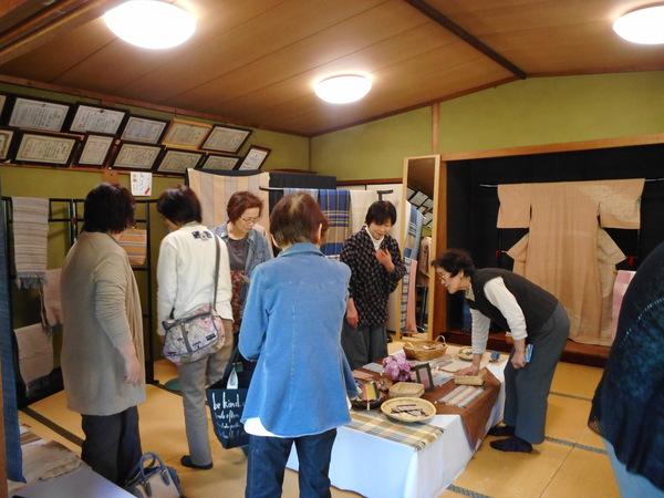 机の上の製品や飾られている製品を見ている女性達の写真