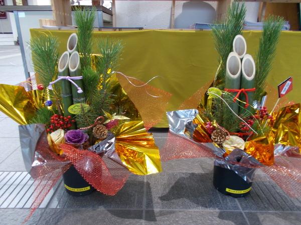 お花や松ぼっくり、赤や金色のシートでデコレーションされた二つの門松の写真