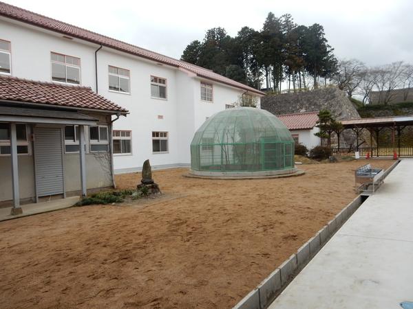 耐震改修工事完成し新しくなった校舎と、網で囲まれたドームのようなものの写真