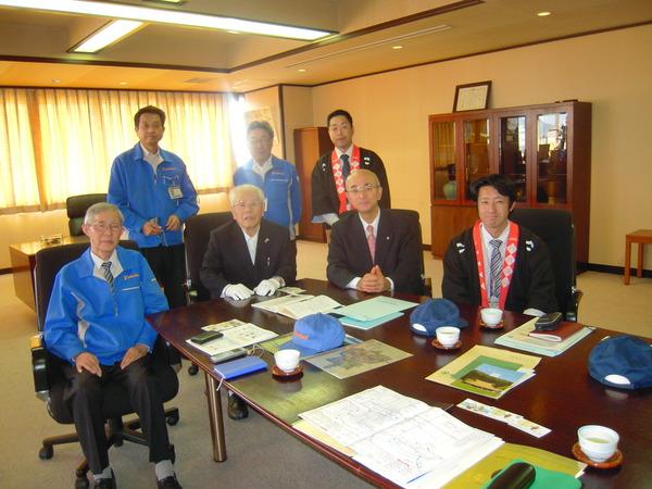 資料や帽子、お茶が置かれているテーブルと椅子に腰かけている北村社長、高鳥会長、酒井市長、市職員とその後ろに立っている蘆田さん、前川さん、市職員の写真