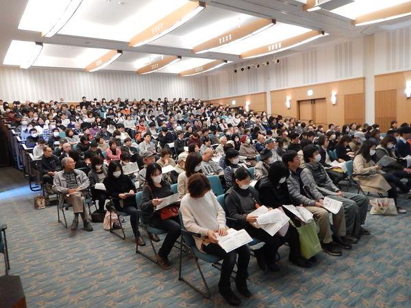 説明会に集まった多くの市民が椅子に座り、資料に目を通している様子の写真