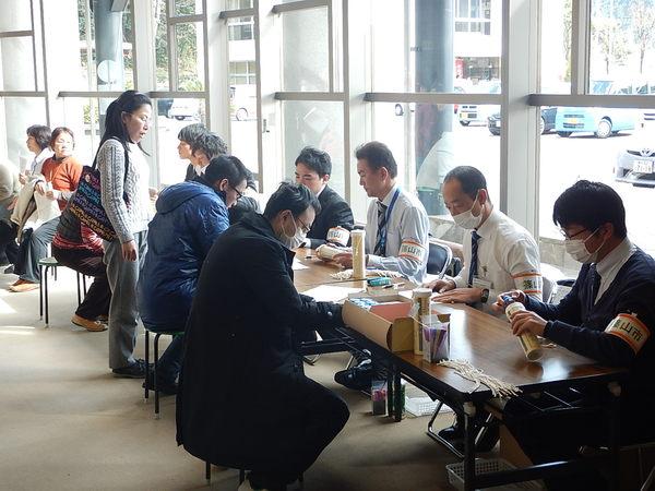 職員の前に座り用紙に記入をしている人々の写真