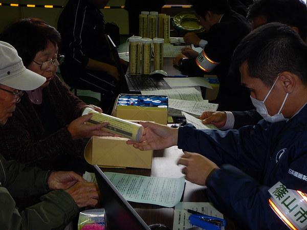 職員が年配の女性に安定ヨウ素剤を配布している写真