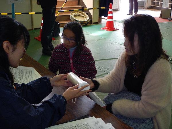 職員が親子に安定ヨウ素剤を配布している写真