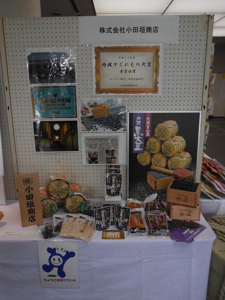写真や新聞記事が飾られた机の上に株式会社小田垣商店の製品が並べられた写真