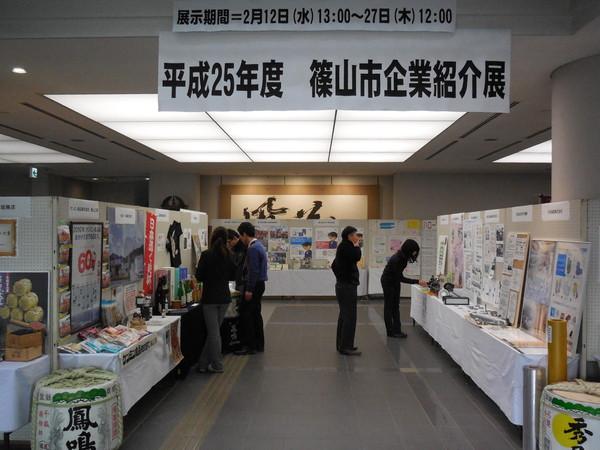 篠山市企業紹介展で、たくさん並べられた製品を、訪れた人々が見ている写真
