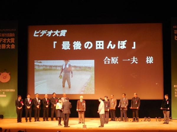 スクリーンにはーンにはビデオ大賞「最後の田んぼ」合原 一夫様とあり、賞を取られた方が並んでいる写真
