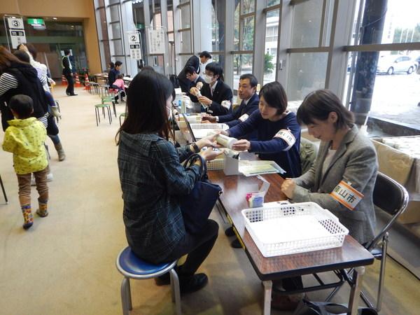 女性市民が安定ヨウ素剤を職員から受け取っている様子の写真