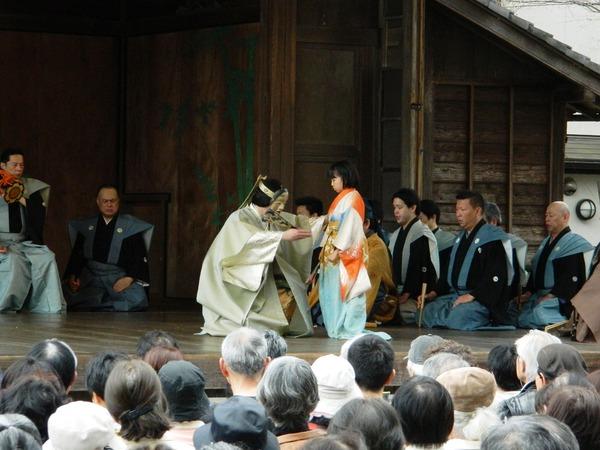 舞台の上で着物を来た子供の前に、能のお面をかぶった大槻さんがしゃがんでいる写真
