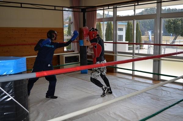 リングで左の青グローブの生徒が左アッパー、右の赤グローブの方がガードしている写真