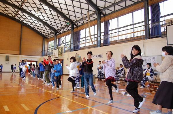 子供達が体育館の中で大きな輪を作り踊りを踊っている写真