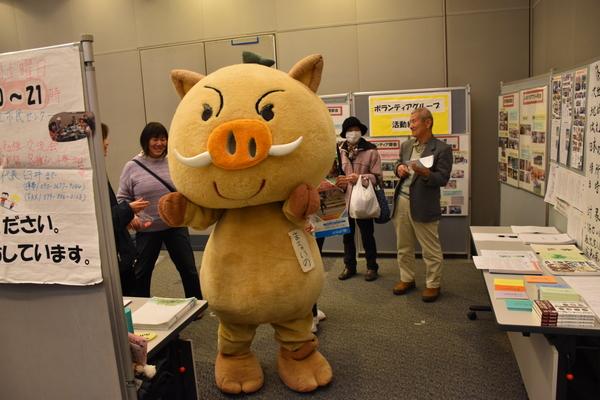 展示コーナーでゆるキャラが両手を挙げて記念撮影している写真