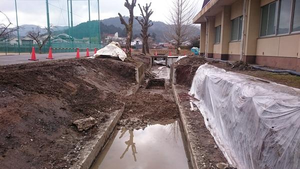 建物横のコンクリート三面張りの水路工事の写真