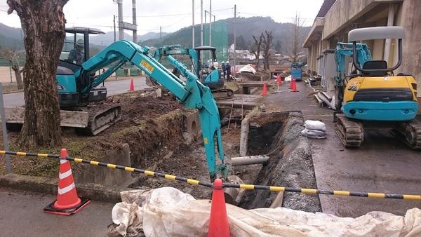 建物横のコンクリート三面張りの水路を重機などを使い工事をしている写真