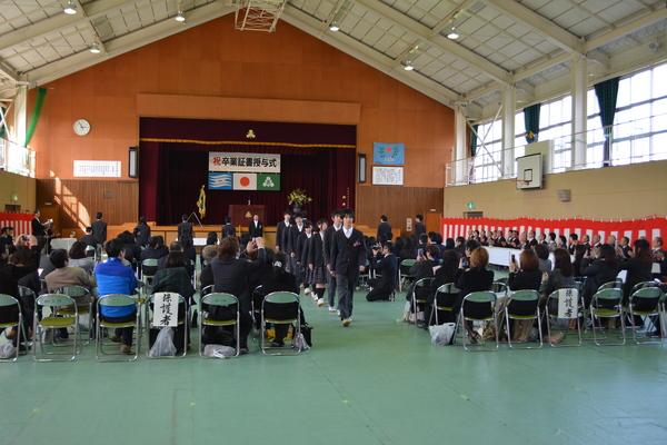 産業高校丹南校卒業式で、卒業生が座っている生徒と保護者の間を退場している写真
