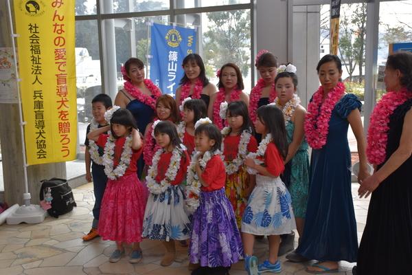 花の首飾りとフラダンスの衣装を身にまとった大人と子供たちの集合写真