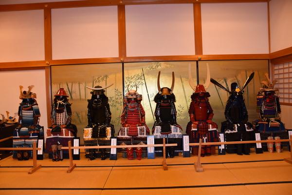 赤や黒の鎧兜が横一列に8体並んでいる写真