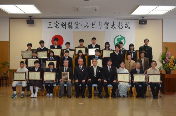 市長と三宅さんが中央に座り受賞者が賞状を持って並んで映っている記念写真