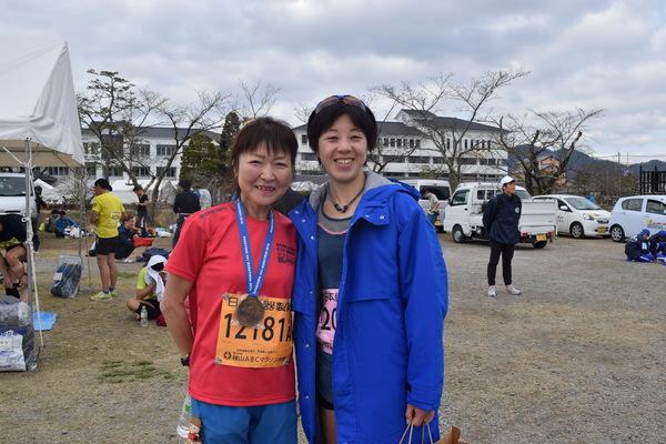 赤いTシャツにメダルを下げた方と、福本 かおりさんが記念写真