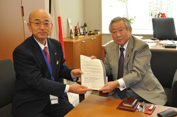 1枚の書類を鴻池 よしたださんと市長が手に持ち記念撮影している写真