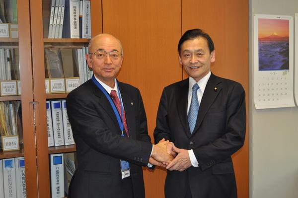 末松 信介議員と市長が握手をしている写真
