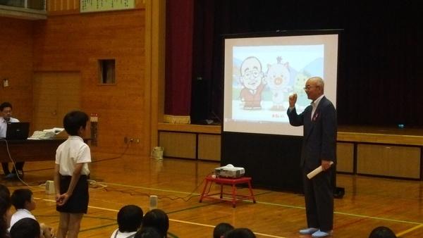 1人の男子生徒が立っていて、スクリーンの前で市長が話をしている写真