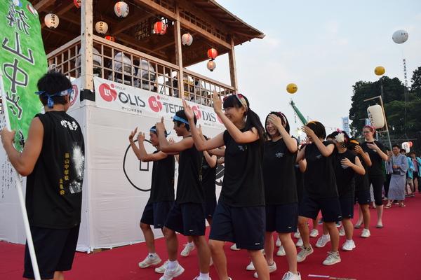 やぐらの下で高校生が黒の上下をきて踊っている写真