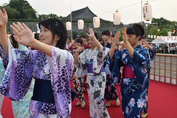 浴衣を着た女性たちが両手を上げ踊っている写真