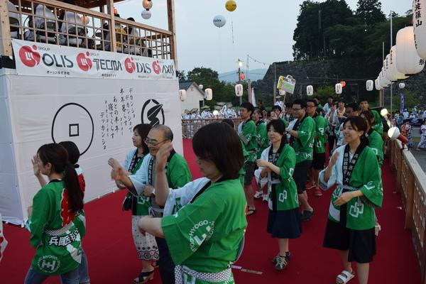 舞台の上で緑色の法被を着た人たちが踊っている写真