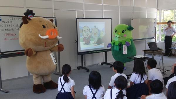イメージキャラクターまるいのとまめりんが前に立ち生徒が見ている写真