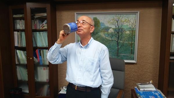 完成した青色の鮮やかなマグカップで飲み物を飲む素振りをしている市長の写真