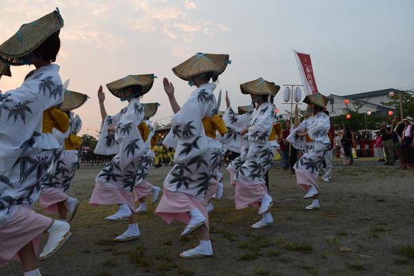 薄暗い中、浴衣を着た女性達が踊っている写真