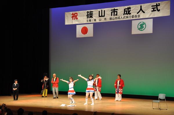 チアリーダーのような白に青いラインの入った衣装を着た女性2人が舞台の中央で両手を広げで踊っている様な様子の写真