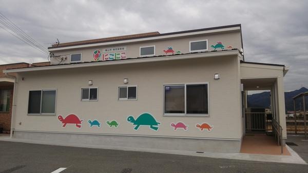 白い外壁にカラフルな6匹の亀のイラストが描かれている病児保育室「にこにこ」の外観写真