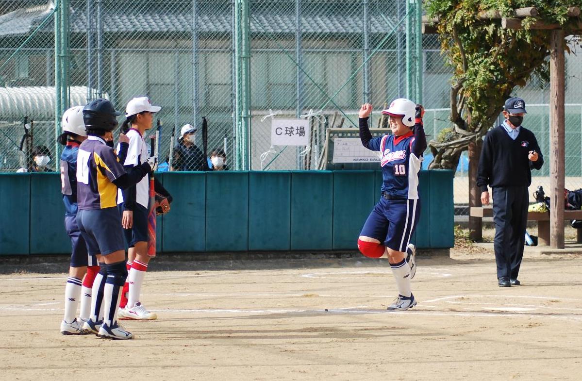 ソフトボールの試合で、ホームインした走者がチームメイトとハイタッチしようとしている