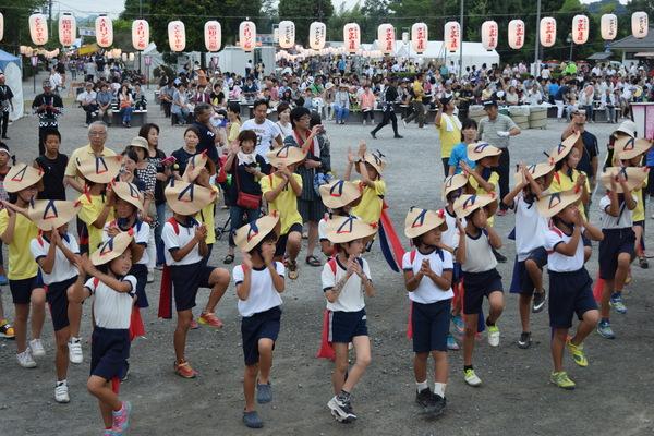 編み笠に体操服姿の女の子らが左足を上げて手拍子をして踊っている写真
