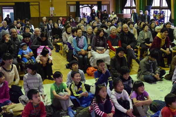 「後川春来いまつり」のステージを観覧している西宮公同幼稚園の子どもたちと後川地区の人たちの写真