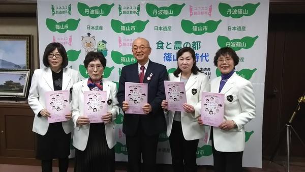 冊子を持って、ソロプチミストささやまの皆さんと市長で記念写真