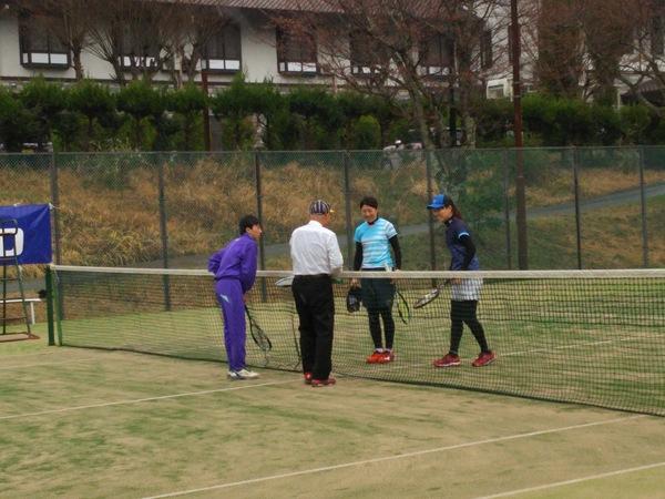 テニスコートの真ん中に集まり4人でお話ししている写真