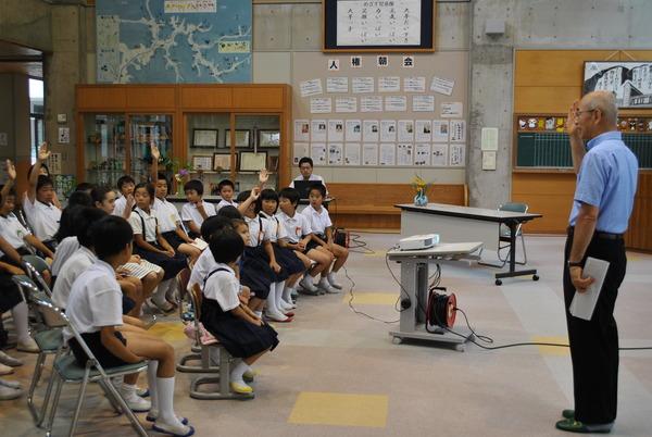 子供達が椅子に座り市長に手を上げている写真